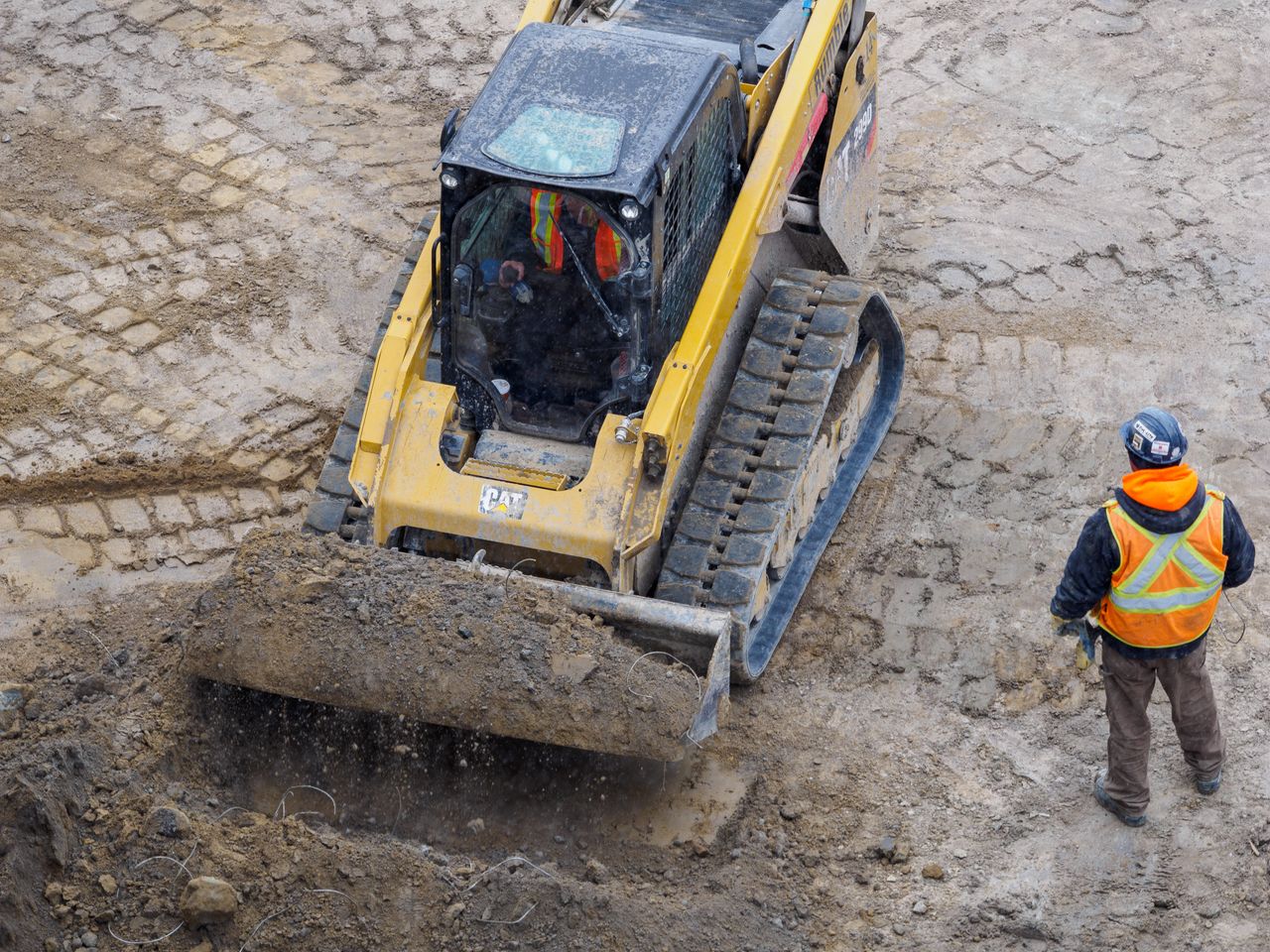 services-02 Top view of a bulldozer and worker on a construction site preparing the ground.