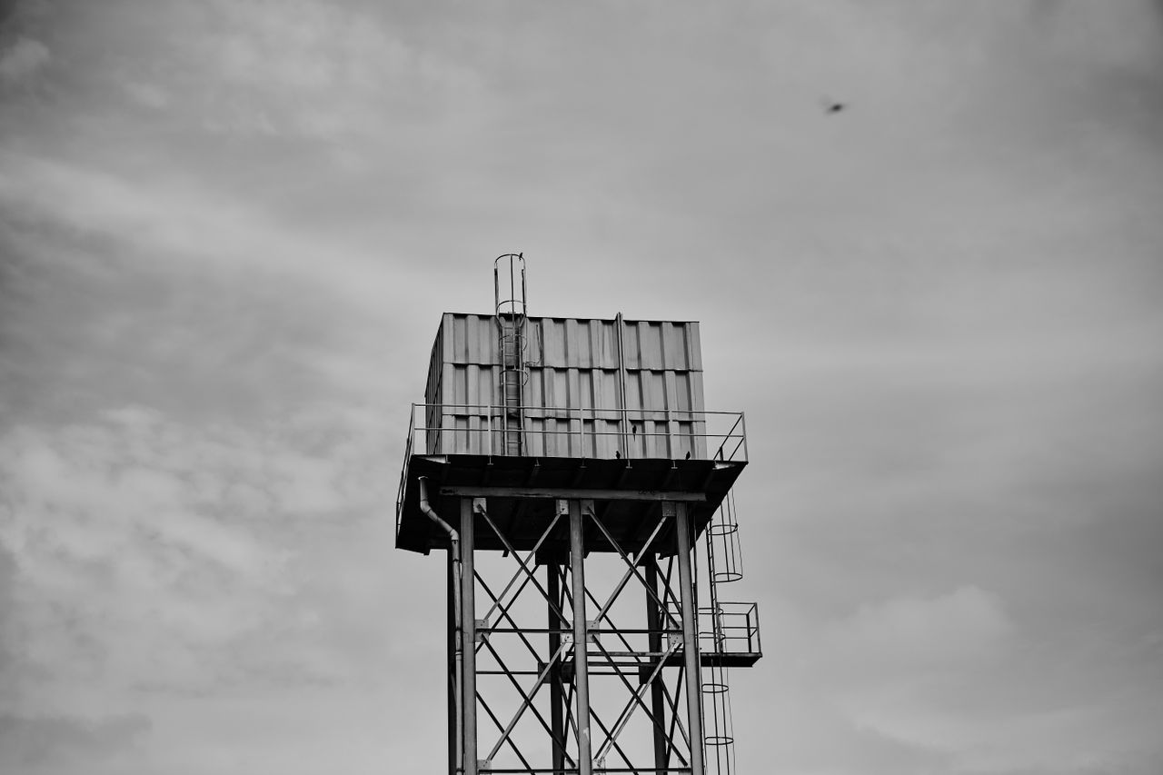 why-choose-us Monochrome image of a tall metal water tower against a cloudy sky.